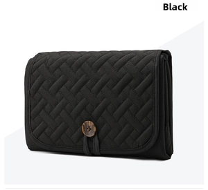 Close-up of black quilted diaper mat bag with wood button and textured fabric detail