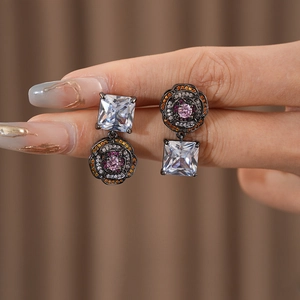 Detailed close-up of asymmetric vintage earrings with square zircon and camellia floral charms
