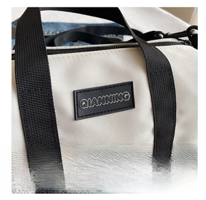 Close-up of white nylon Boston bag showing fine fabric texture and QIANNING logo detail