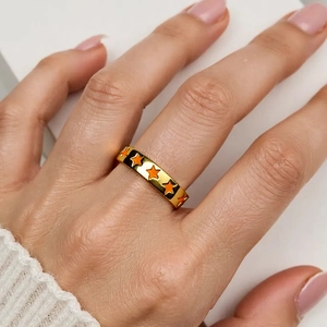 Fashionable adjustable gold ring with orange star patterns worn on a woman finger