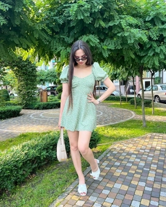 Détail d'une robe courte fleurie verte avec manches bouffantes et col en V profond