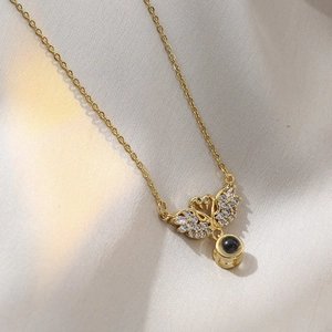 Detail of golden swan pendant with clear zircons and black bead on a sleek chain