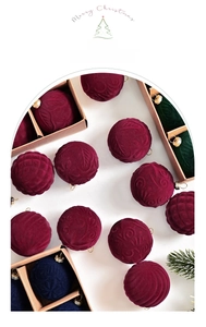 Detail of velvet Christmas balls with embossed texture in deep burgundy and dark blue hues