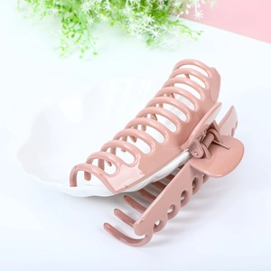Large matte pink hair claw clip for thick hair displayed on a decorative white plate