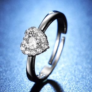 Macro shot of silver heart ring with multiple white pave diamonds on a blue background