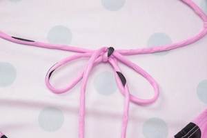 Détail du tissu rose à pois bleu clair avec une attache délicate en forme de nœud rose