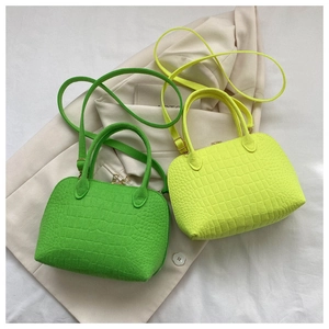Detail view of mini neon green and yellow shell bags with crocodile texture and straps