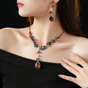 Close-up of vintage necklace and earrings set with colorful teardrop gemstones on model