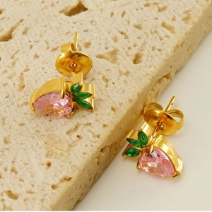 Macro shot of gold strawberry stud earrings with pink drop-shaped crystals and green leaves