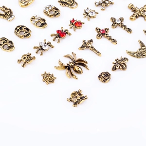Macro shot of vintage gold alloy nail charms including skulls, crosses and spiders