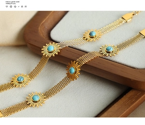 Detail of woven gold-plated flower bracelet with turquoise stone in a wooden tray