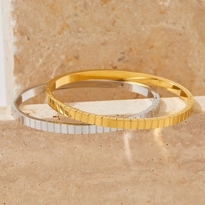 Bracelets modernes en acier inoxydable rayé or et argent sur un support minimaliste