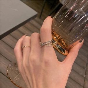 Detail of layered gold rings with small diamonds worn on a finger holding a glass
