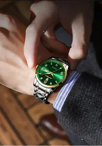 Macro detail of men's business watch with green sunburst dial and dual calendar window