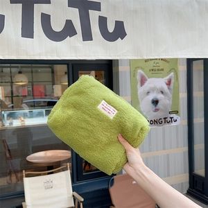 Detail of soft green plush shearling cosmetic bag with inspirational woven label text