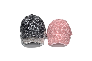 Détail de casquettes de baseball empilées en noir, rose et beige avec motifs monogrammes