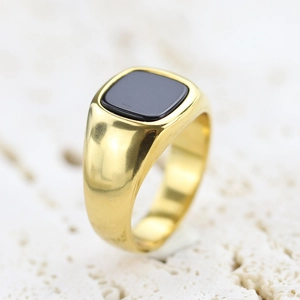 Close-up of a gold-plated stainless steel ring with a black rectangular enamel inlay