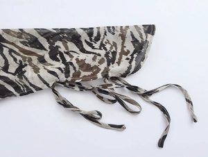 Macro detail of tiger print chiffon fabric featuring waist ties and contrast stitching