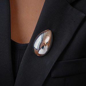 Close-up of a silver teardrop brooch with a mirror finish on a black suit lapel