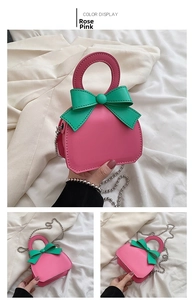 Detail view of mini rose pink bag with green bow and silver bead chain strap