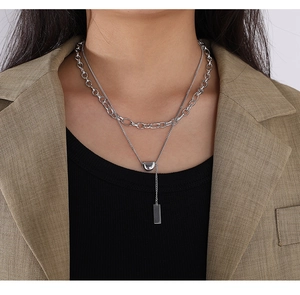 Detail of silver double-layered stainless steel necklace with geometric lucky bean pendant
