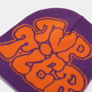 Macro detail of purple knit beanie featuring bold orange jacquard heart lettering