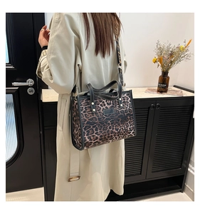 Detail of leopard print tote bag with black leather trim and wide adjustable strap