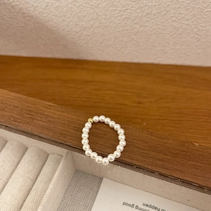 Detailed macro of a stretch pearl ring featuring mini white pearls and one gold bead