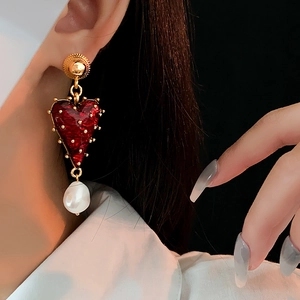 Vintage heart earrings with red enamel and irregular pearl drop worn by a model