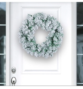 Detail of a flocked Christmas wreath with snow effect hanging on a white front door