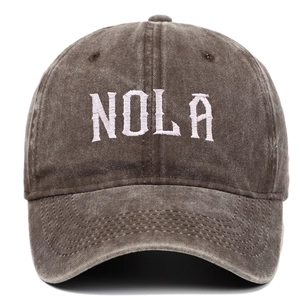 Detailed close-up of vintage washed cotton NOLA embroidery on a dark brown baseball cap