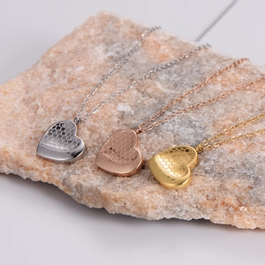 Three heart honeycomb necklaces in gold, silver, and rose gold on a natural stone background