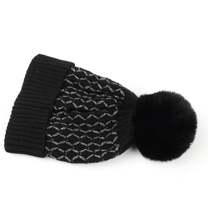Detailed knit texture of black silver-wire plaid beanie with fluffy faux fur pompom