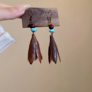 Detail view of ethnic shell tassel earrings with turquoise beads on wooden card