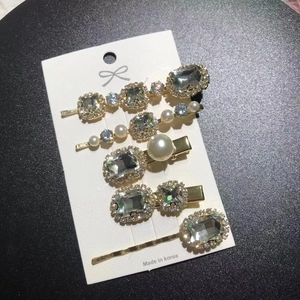 Close-up of 5-piece gold hair clip set with pearls and emerald-cut crystals on a display card