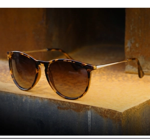 Close-up of retro tortoiseshell sunglasses with brown gradient lenses on metal block