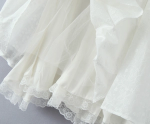 Détail de l'ourlet en dentelle blanche et broderie sur une robe en coton et tulle
