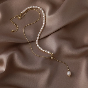 Macro shot of baroque freshwater pearls with golden snake chain on elegant brown silk