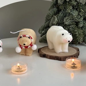Polar bear candles with red scarf on wood base and burning tea lights for home decor