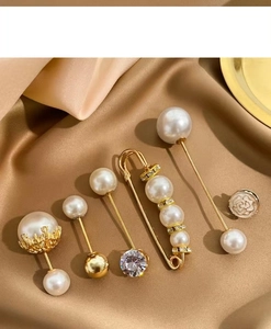 Detailed view of luxury gold alloy pearl and rhinestone brooches on champagne silk fabric