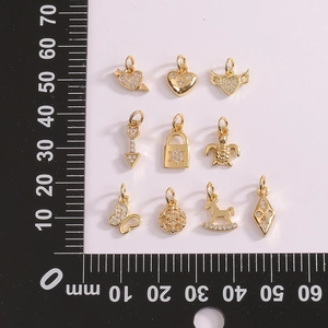 Vue détaillée de dix pendentifs dorés avec une règle pour comparer la taille