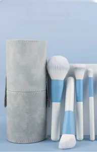 Detail of four blue makeup brushes in a stylish light blue leather storage tube container