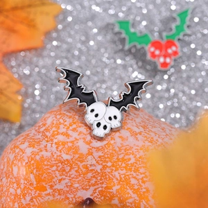 Halloween skull and bat wing enamel brooch on a festive pumpkin and maple leaf backdrop