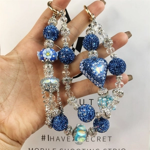 Detail of blue sequined heart beads and glass flowers on a handmade phone charm chain