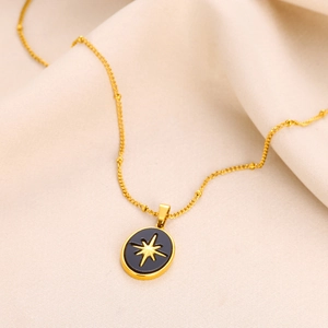 Macro shot of gold stainless steel necklace featuring a black oval pendant with starburst