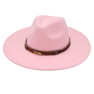 Detail of pink wide brim fedora hat featuring woven band and golden feather pendant