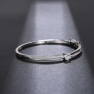 Detailed close-up of a silver crossover bangle with a central round zircon and small stones