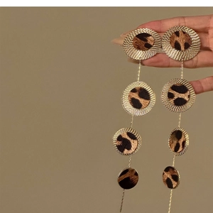 Detail of layered leopard print round earrings with golden sunburst textured frames
