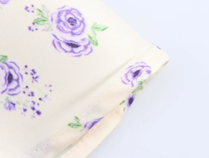Détail macro d'imprimé floral violet sur satin crème avec coutures de précision