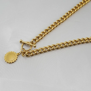 Detailed shot of golden Cuban link necklace with sunflower pendant and OT clasp closure